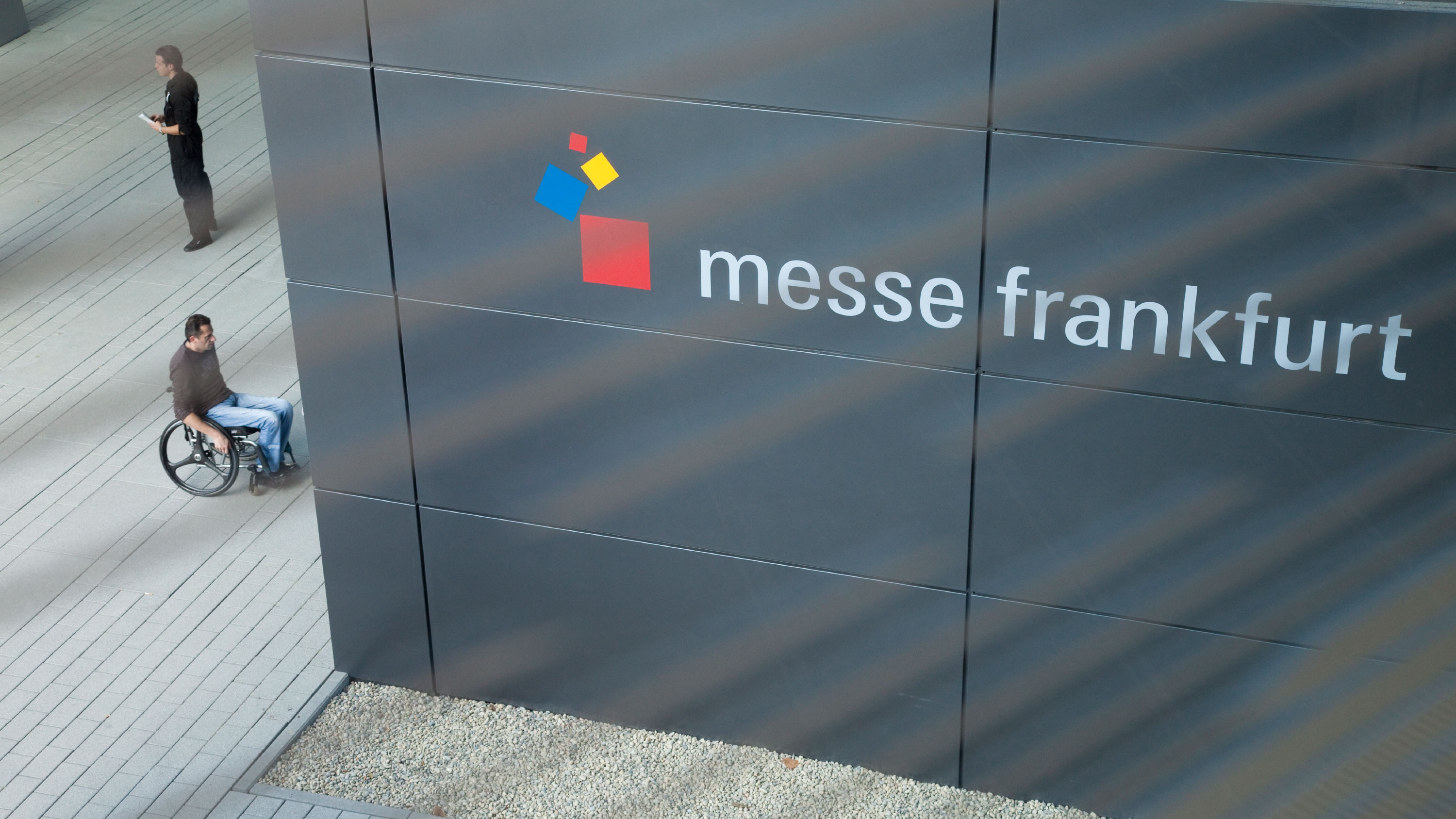 Man in a wheelchair drives to the entrance of Messe Frankfurt