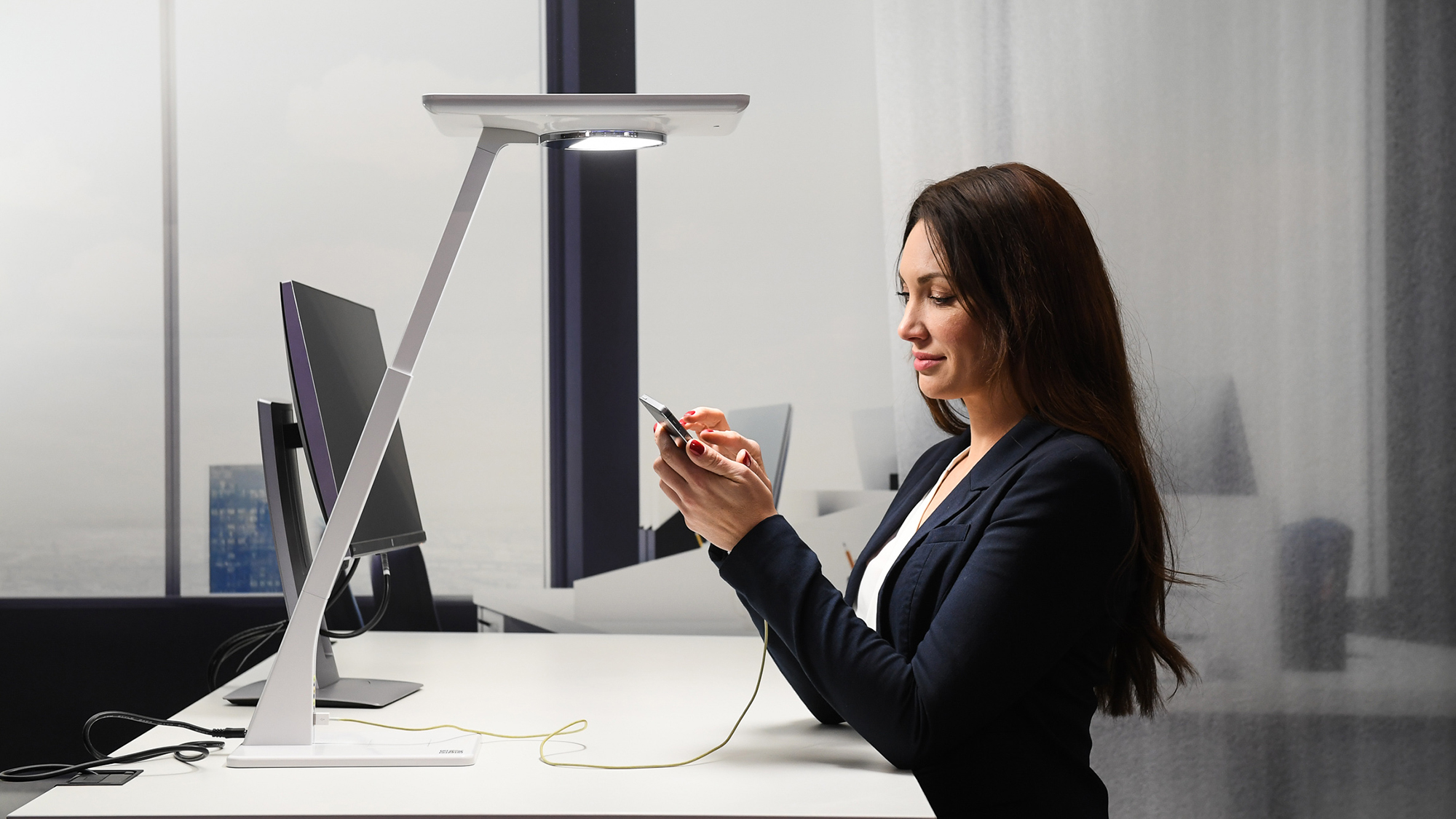 Woman with smartphone in front of a table lamp