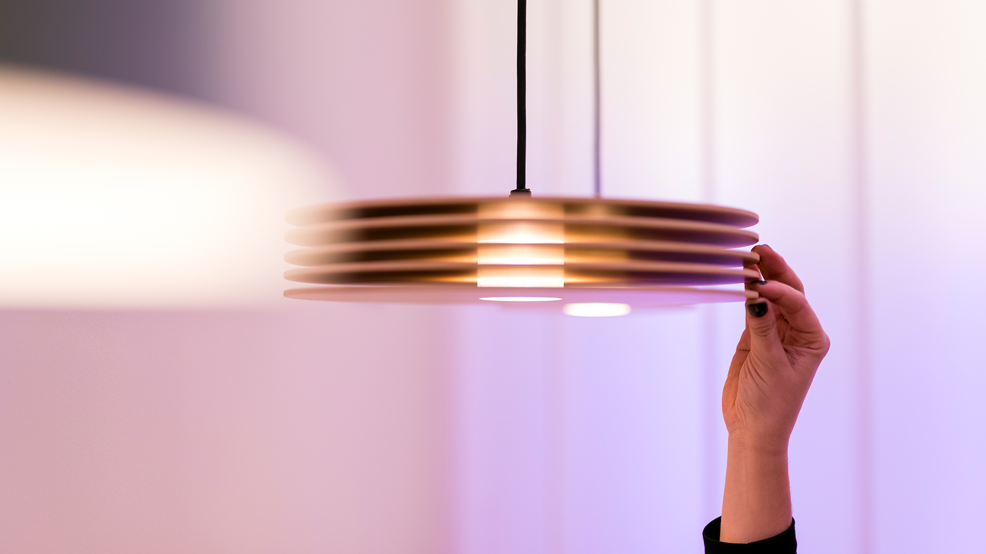 A woman is touching a hanging lamp