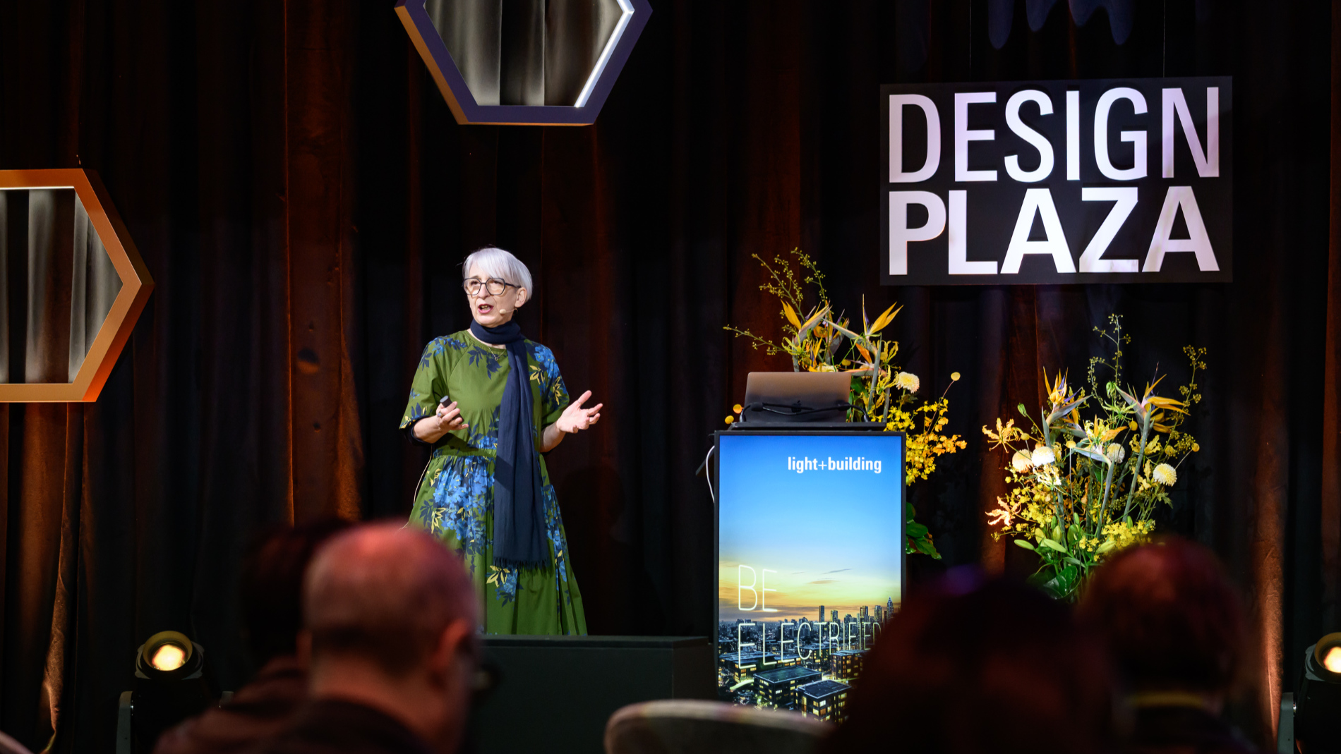 A talk on a stage in the Design Plaza